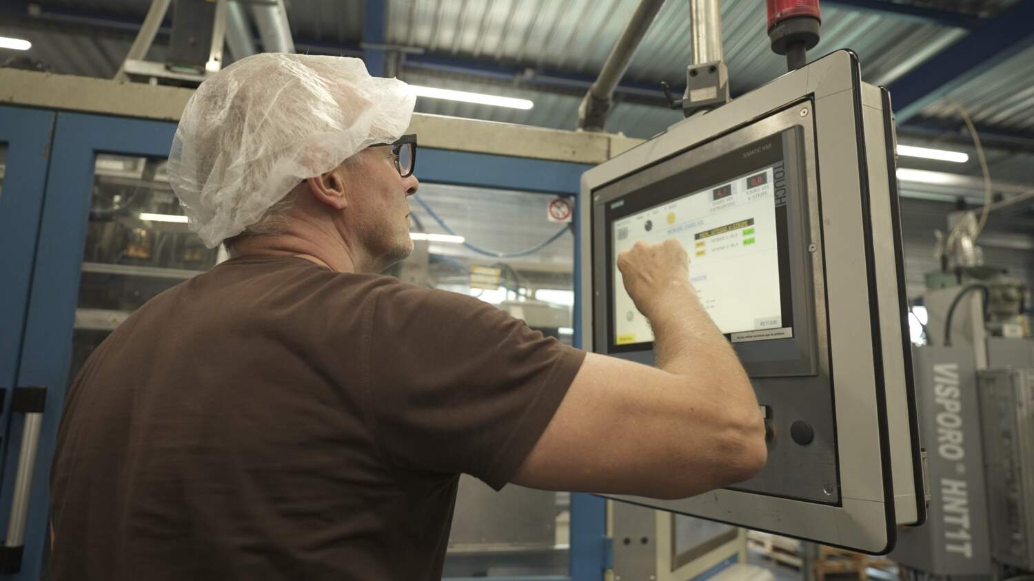 PHOTO D'UN ARTISAN ENTRAIN DE RÉGLER UNE MACHINE POUR LA FABRICATION DE PRODUITS PLASTIQUES